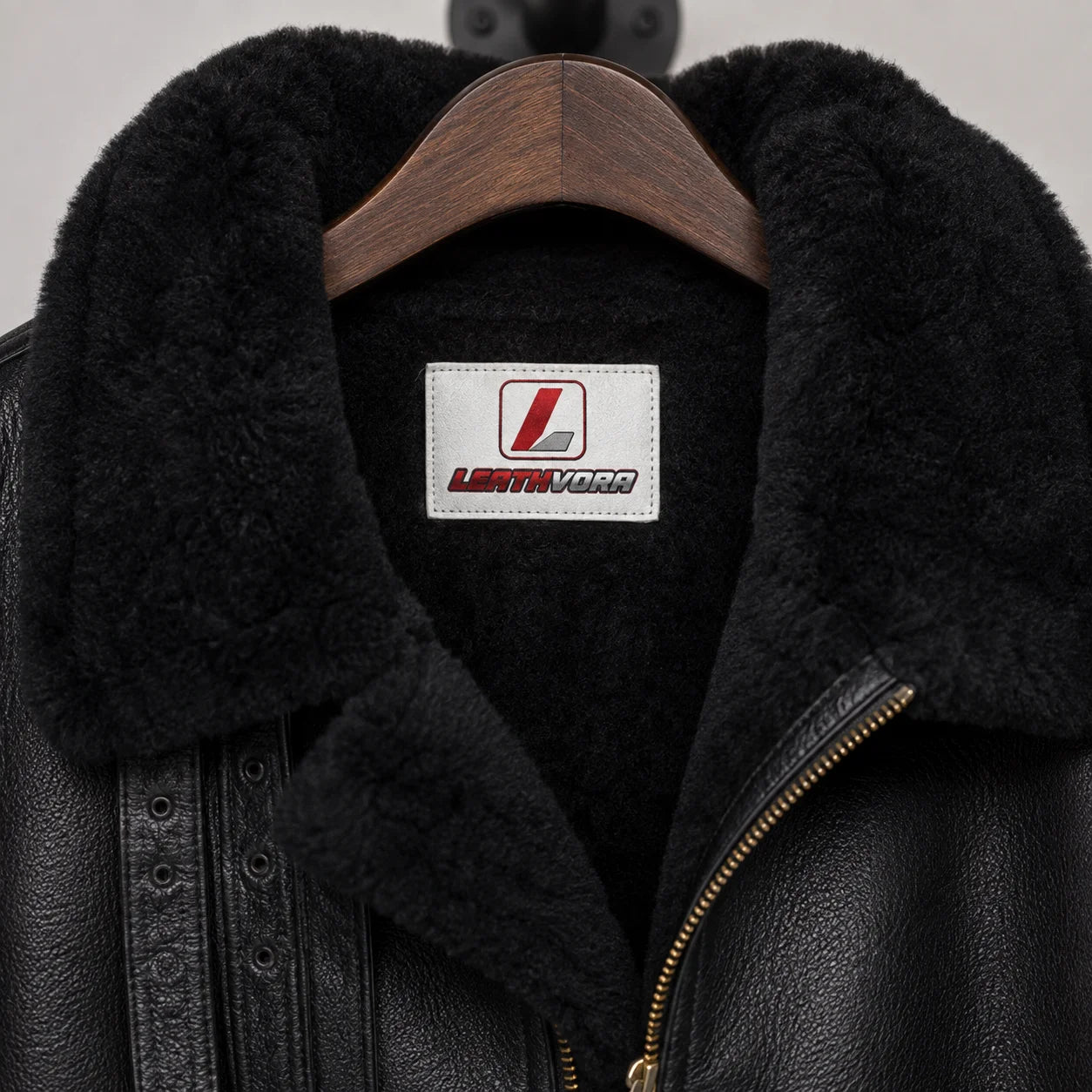 Close-up of black shearling collar and interior with Leathvora neck label, leather grain and front zip detail