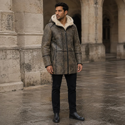 Three-quarter outdoor view of brown shearling aviator coat with cream-lined hood, front zip and slim black trousers