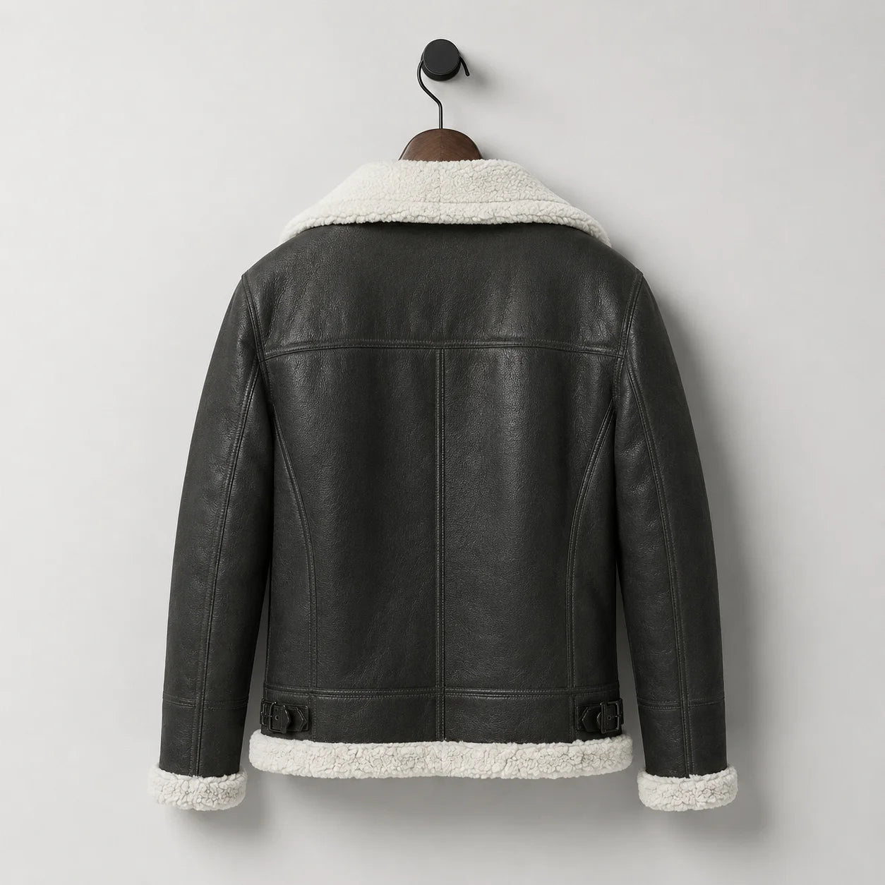 Hanging rear view of men’s black aviator jacket with white collar and hem trim plus adjustable rear waist buckles