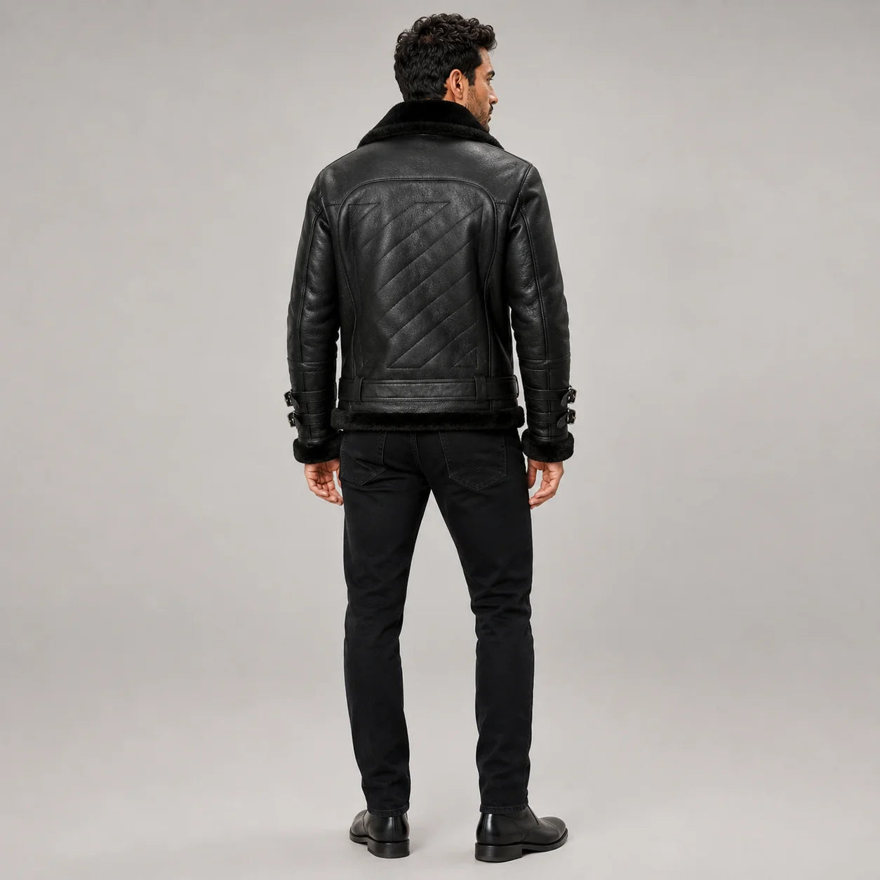 Rear model view of men’s black B3 jacket showing diagonal quilted back panel, waist belt and black fleece hem