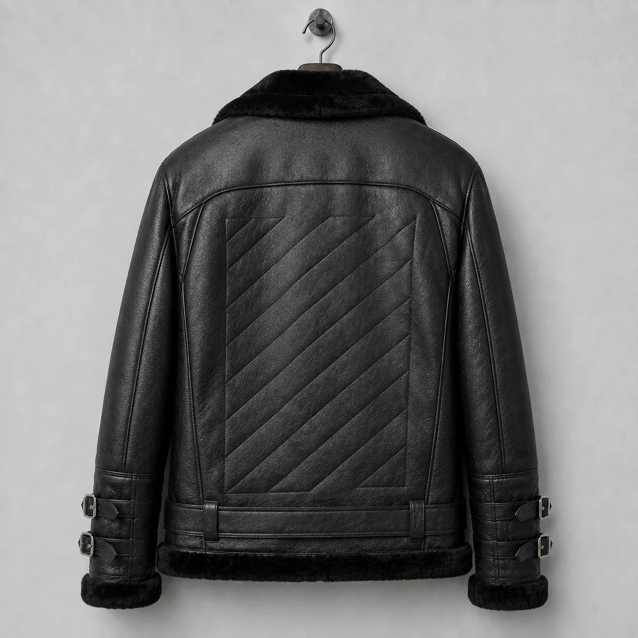 Hanging rear view of black sheepskin flight jacket with large diagonal quilted centre panel and belted lower back