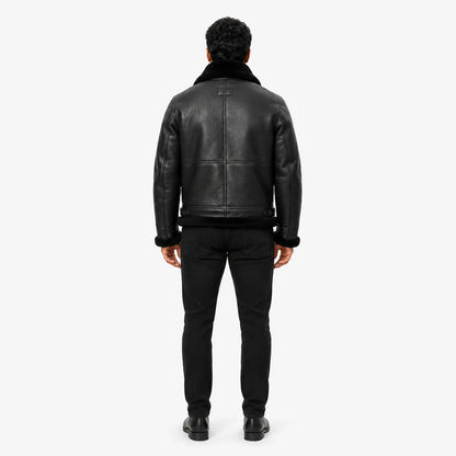Rear studio view showing textured black leather back panels, black shearling collar, cuffs and trimmed hem
