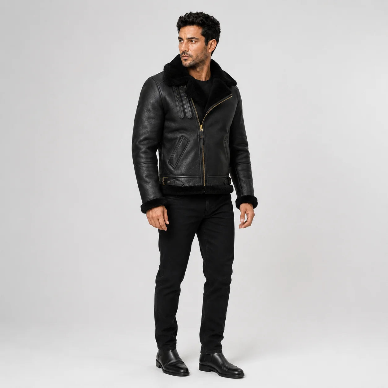 Three-quarter studio view of black shearling aviator jacket with front zip, angled pockets and waist buckle tabs