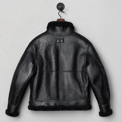 Back hanging view of black sheepskin flight jacket showing central seam, textured leather and shearling hem trim