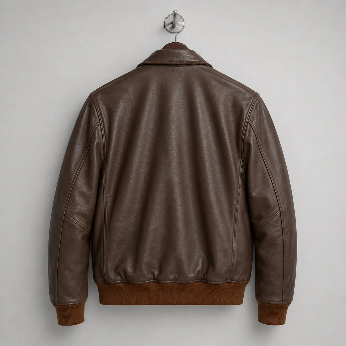 Rear hanger view of brown leather bomber jacket showing clean back panel, long sleeves and rib-knit waistband