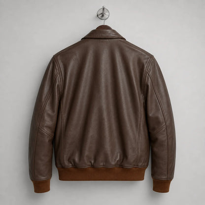 Rear hanger view of brown leather bomber jacket showing clean back panel, long sleeves and rib-knit waistband