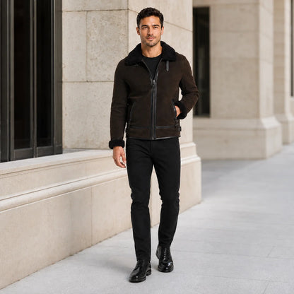 Man wearing dark brown aviator jacket with black jeans and boots in a refined stone-building setting