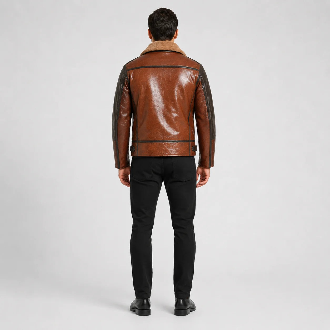 Rear model view of brown leather aviator jacket showing dark shoulder panels, back yoke, piping and waist adjusters