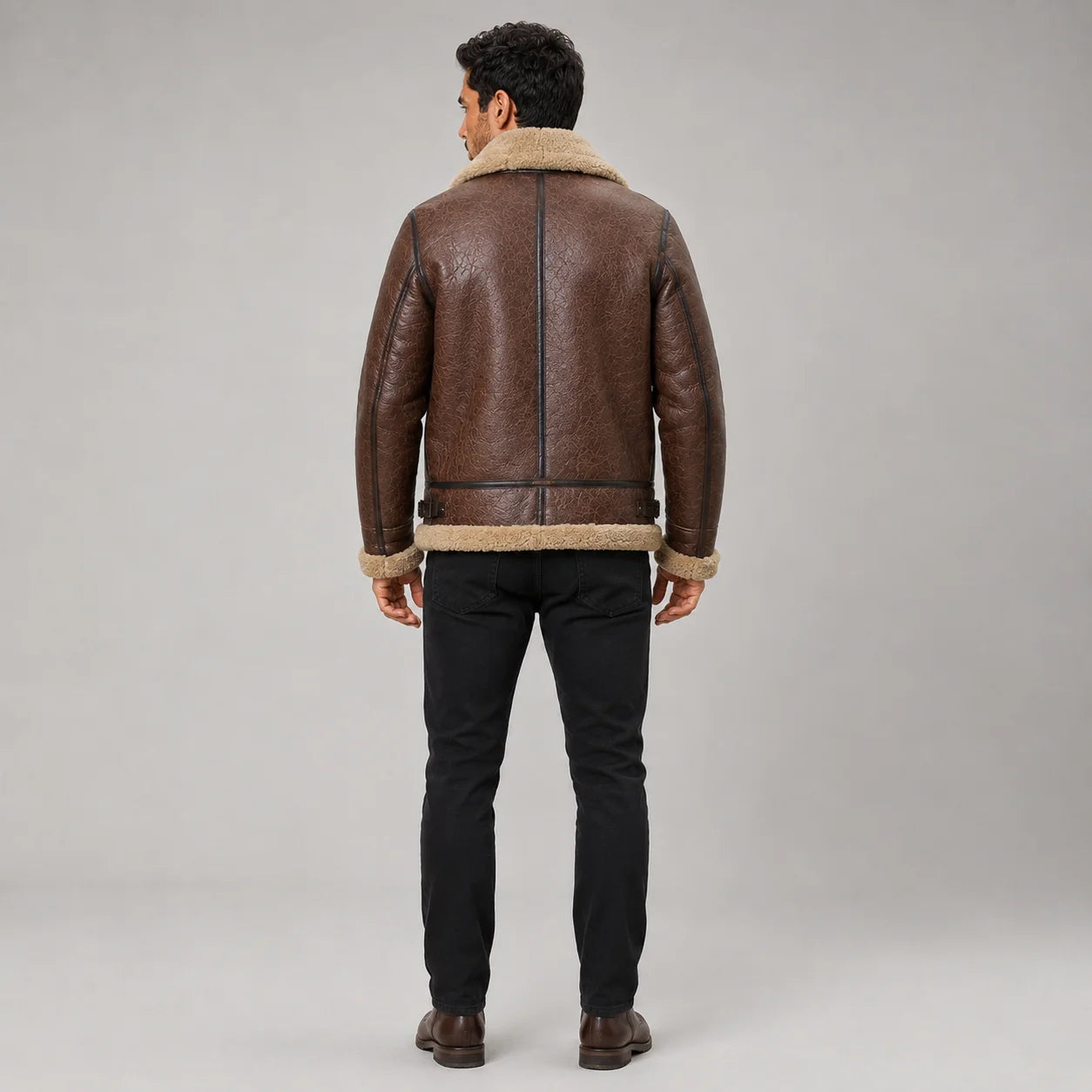 Rear studio view of brown B3 flight jacket showing cream shearling collar and hem, dark piping and waist adjustment tabs
