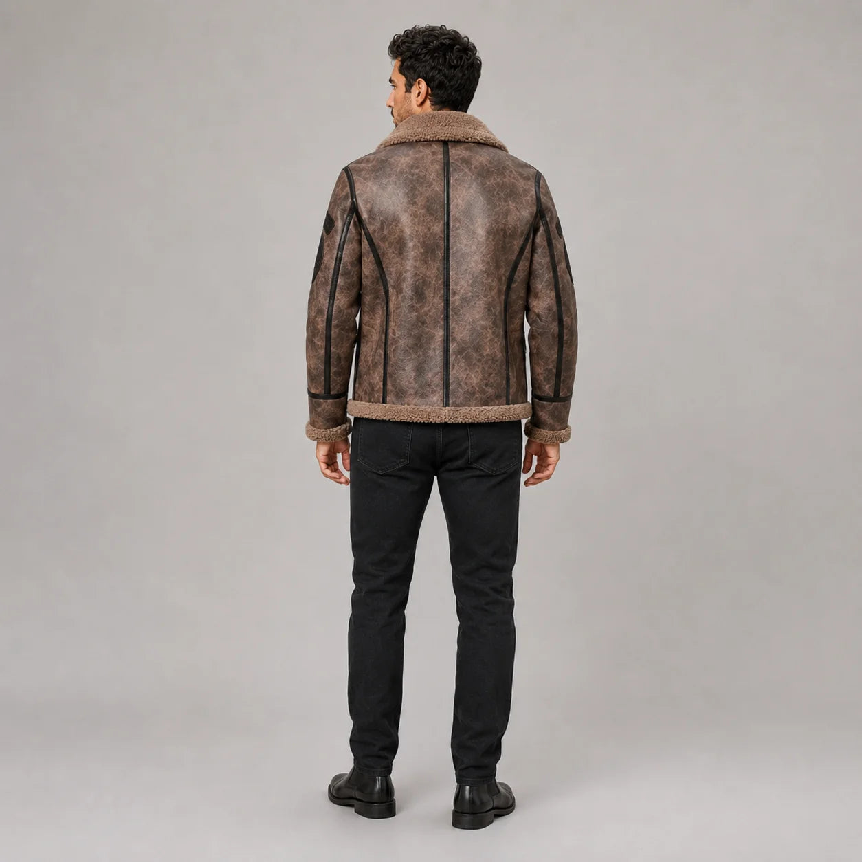 Rear view of men’s brown flight jacket showing plush collar, black centre trim and curved contrast back piping