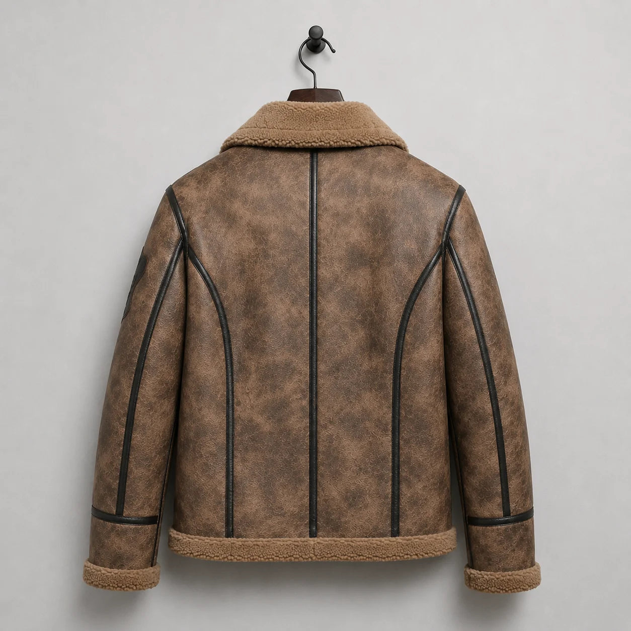 Hanging rear view showing distressed brown B3 jacket with black curved piping, centre strip and plush hem