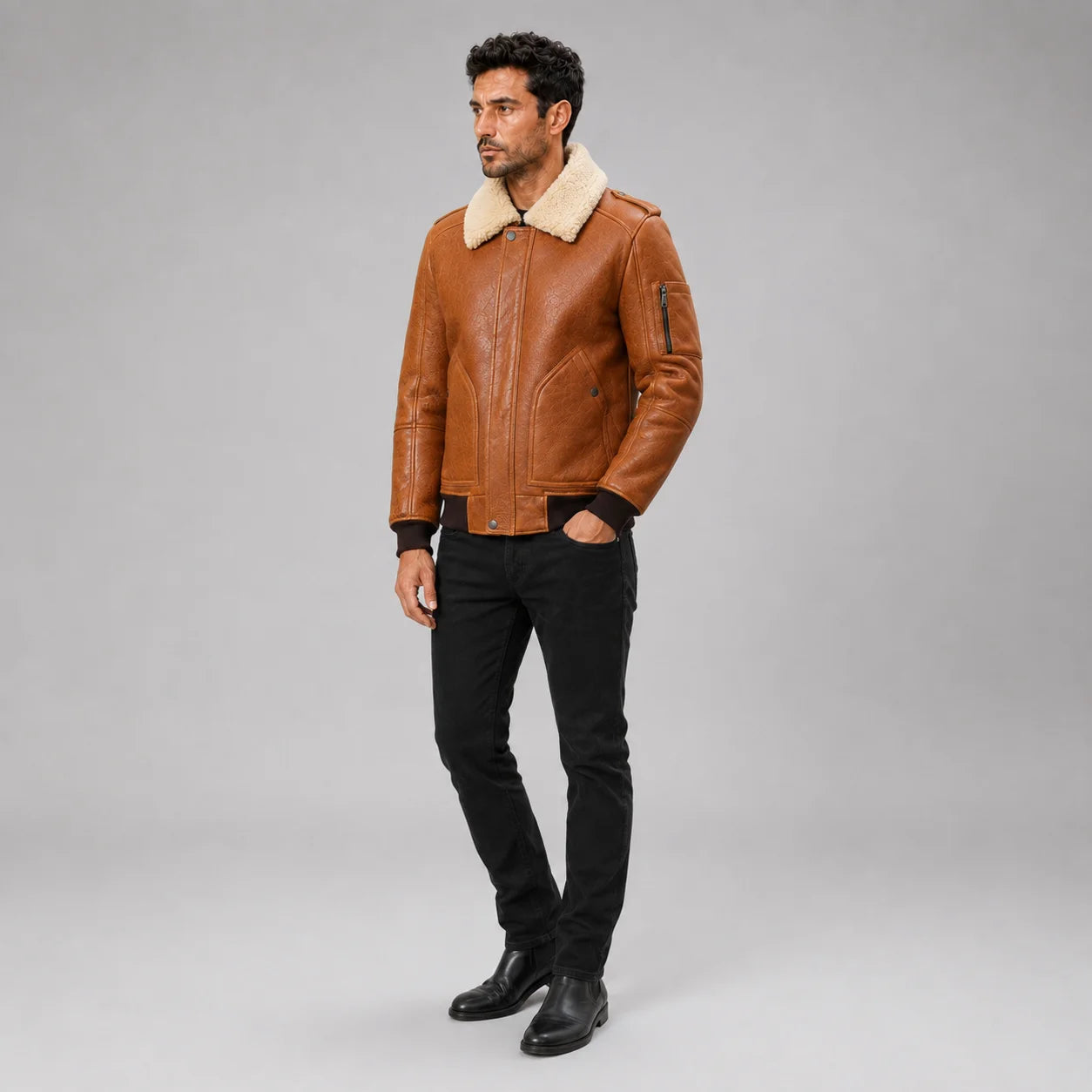 Three-quarter view of men’s brown aviator bomber with cream collar, sleeve zip pocket and black jeans