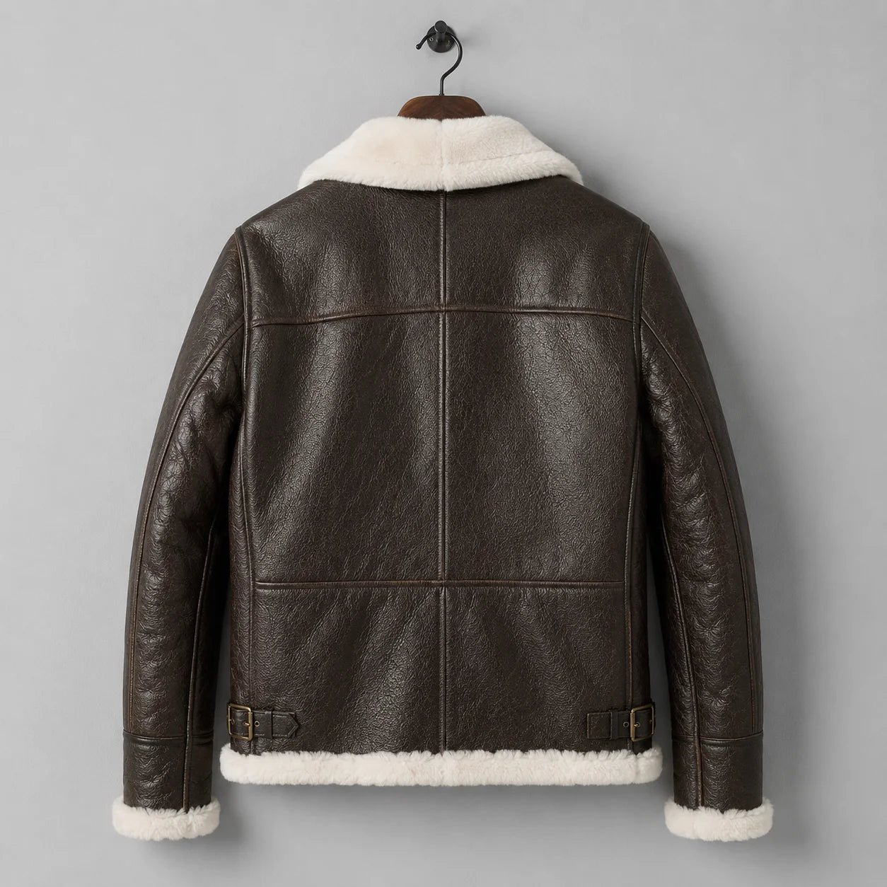Hanging back view of men’s brown B3 jacket with leather panel seams, cream collar, cuffs and shearling hem.