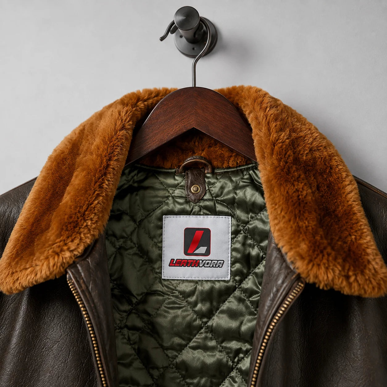 Close-up of brown G-1 style leather jacket with rust plush collar, olive quilted lining and Leathvora neck label