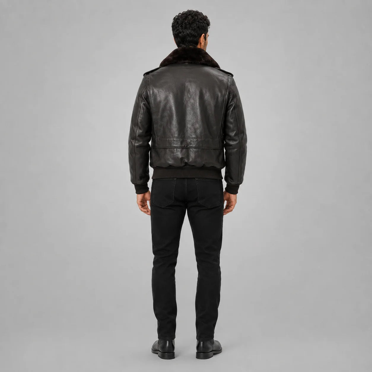 Full-length rear view of men’s brown leather bomber jacket showing fur collar, back panel seams and ribbed waist