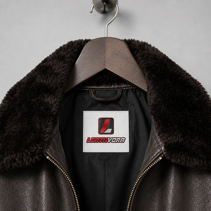 Close-up of dark plush collar, brown textured leather, black inner lining and Leathvora neck label on flight jacket