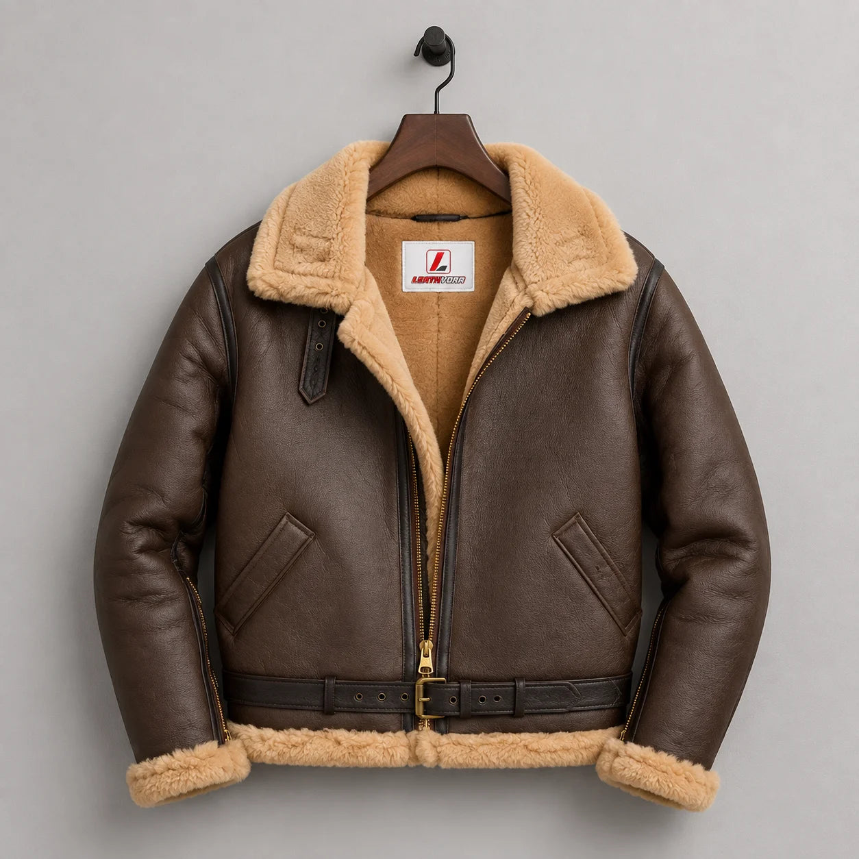 Hanging front view of brown RAF B3 bomber showing tan lining, wide collar, front zip, pockets, belt and fur-trimmed cuffs.