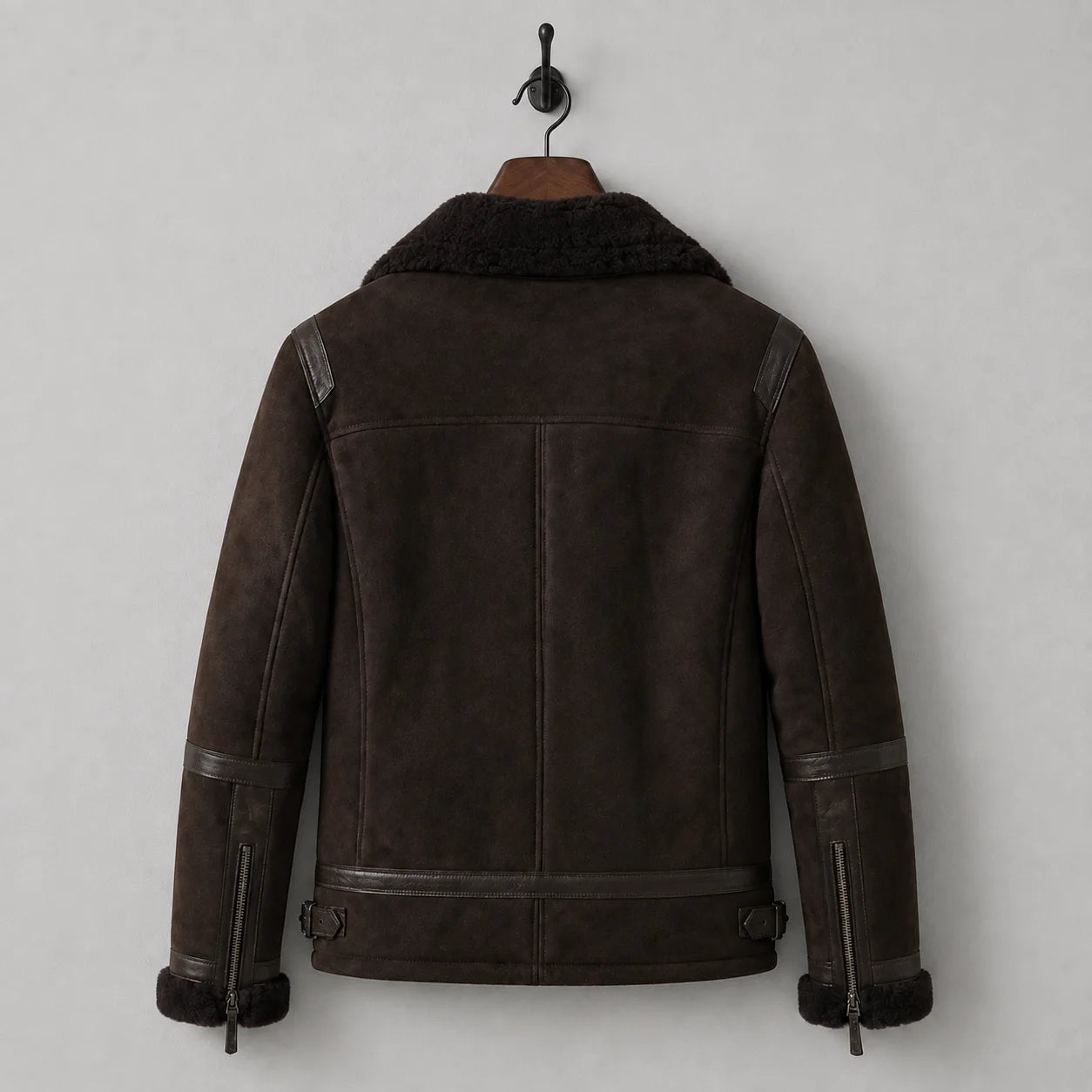 Hanging rear view of dark brown flight-style jacket with shoulder yoke, sleeve trim and adjustable waist tabs