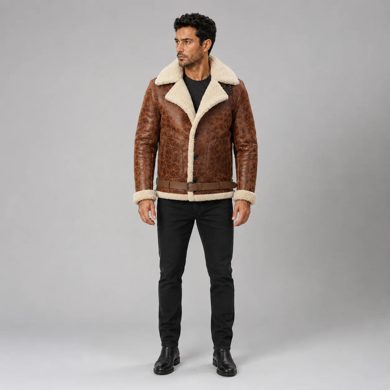Front studio view of man wearing brown sheepskin aviator jacket with cream spread collar, waist belt and patch pockets