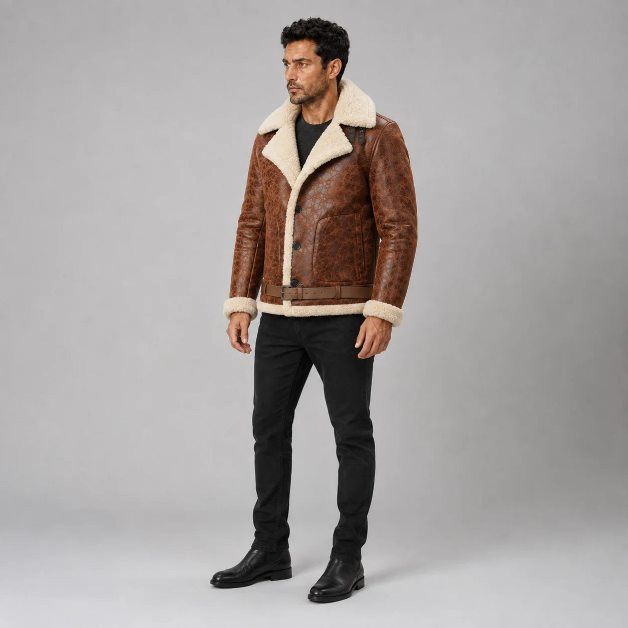 Three-quarter studio view of men’s brown shearling aviator jacket with button front, belt and cream trimmed cuffs