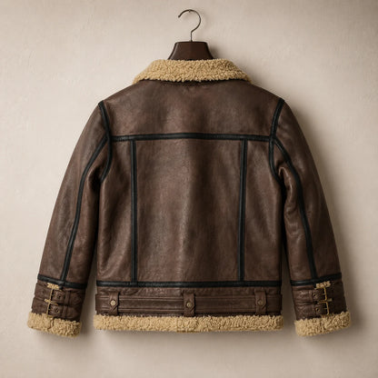 Hanging rear view of brown sheepskin jacket showing structured back panels, dark piping, waist belt and double cuff buckles