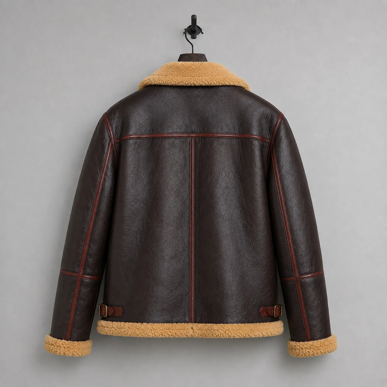 Hanging rear view of dark brown flight jacket with tan hem trim, burgundy piping, centre seam and waist tabs