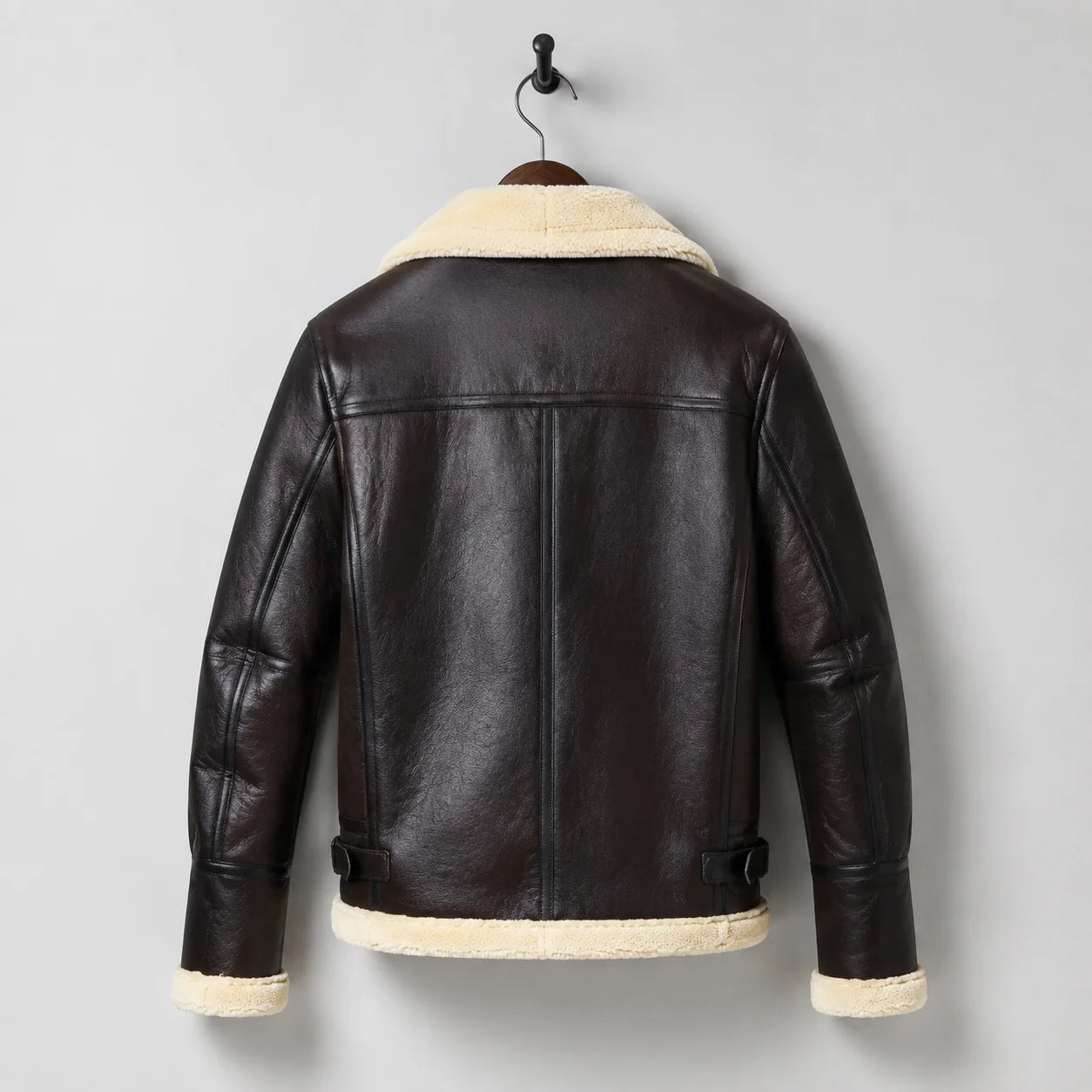 Hanging rear view of men’s brown aviator jacket with cream collar and hem trim, shoulder yoke and vertical back seams.