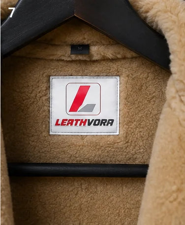 Close-up of tan fleece-style jacket interior with stitched Leathvora neck branding and dark brown leather edge