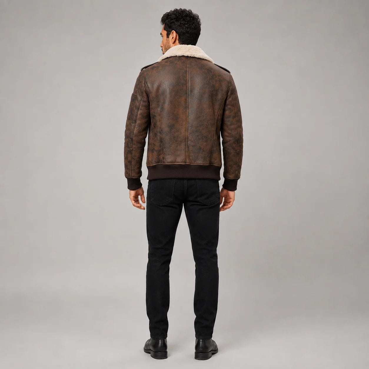 Rear studio view of men’s dark brown flight jacket showing clean back panels, cream collar and rib-knit waistband