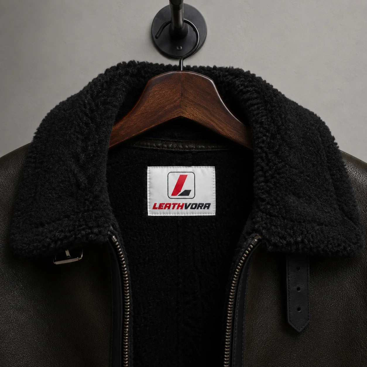 Close-up of black plush aviator collar and lining with Leathvora neck label, zipper and adjustable collar strap