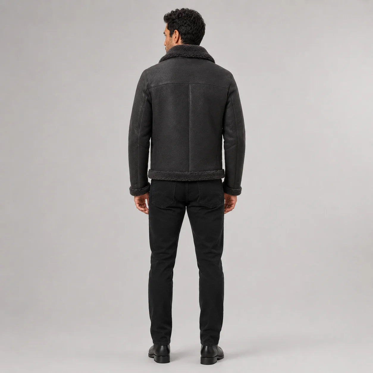 Rear studio view of charcoal aviator jacket showing shoulder yoke, centre seam and dark plush collar and hem