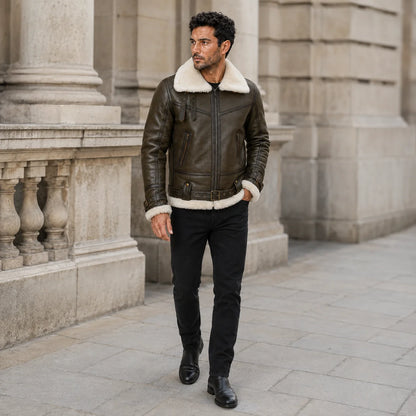 Walking lifestyle view of men’s olive leather flight jacket with cream shearling trim, buckle waist and zipped pockets