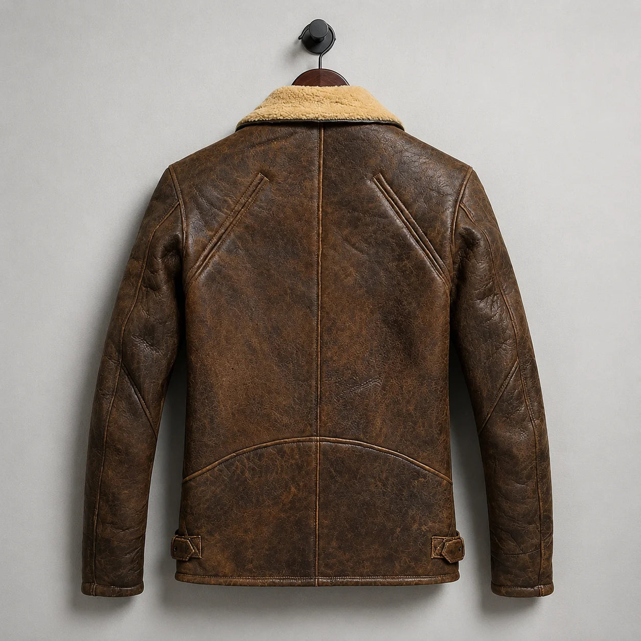 Hanging rear view of brown biker jacket showing distressed finish, curved back construction and adjustable waist tabs