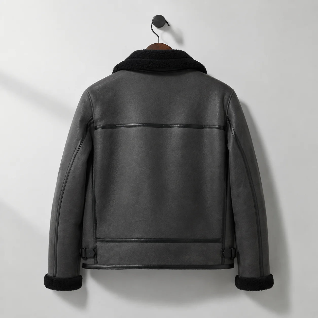 Hanging back view of men’s grey flight jacket with horizontal rear seam, panelled back and side buckle adjusters