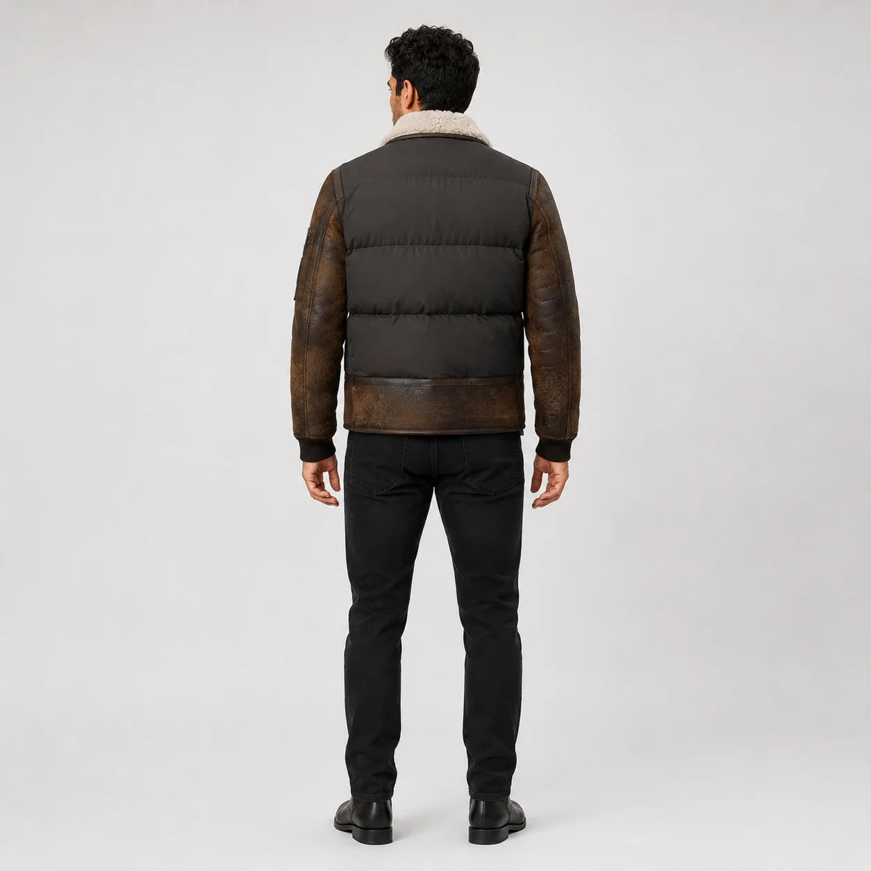 Rear model view showing dark padded back panels, distressed brown leather sleeves and ribbed cuffs.