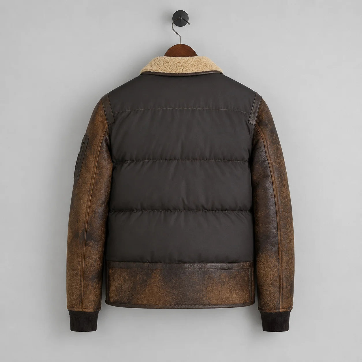 Hanging rear view showing quilted dark brown puffer body, distressed leather sleeves and leather lower panel.