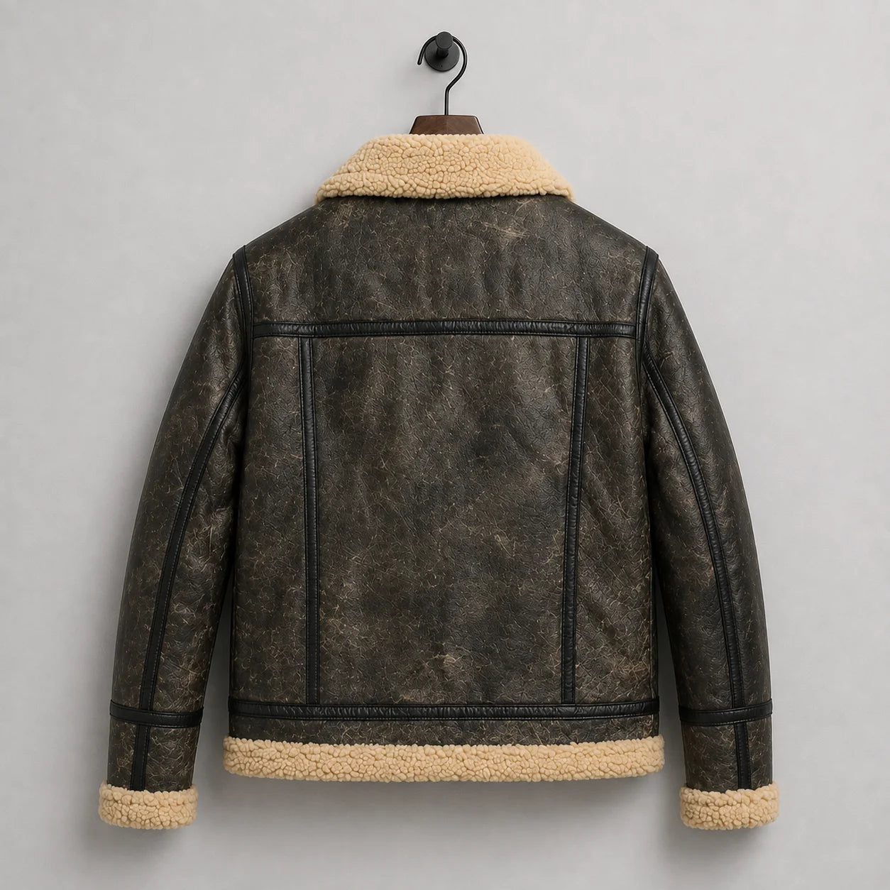 Hanging rear view of dark distressed sheepskin jacket with horizontal shoulder yoke, vertical seams and cream trim